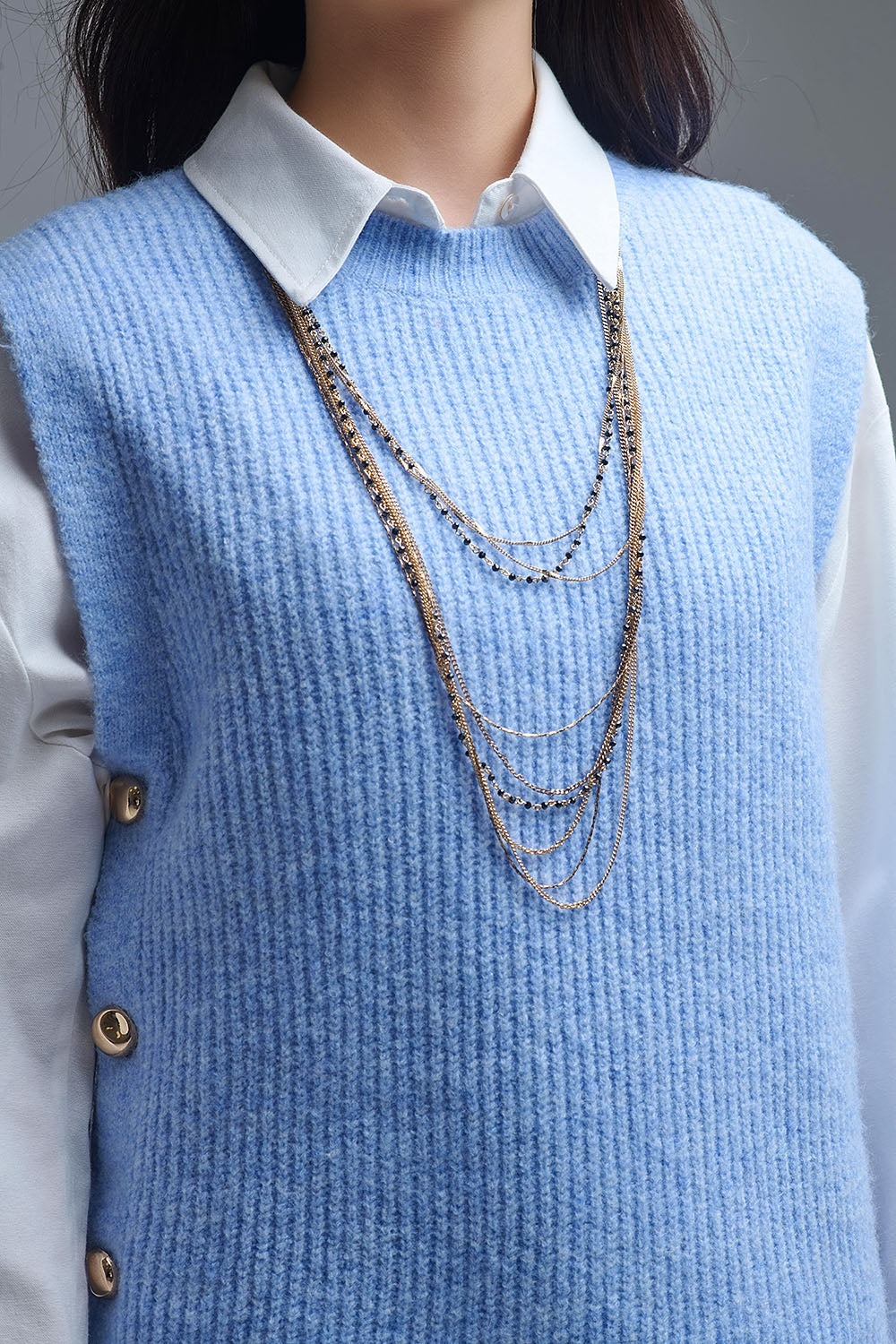 Blue sleeveless sweater with gold buttons on side