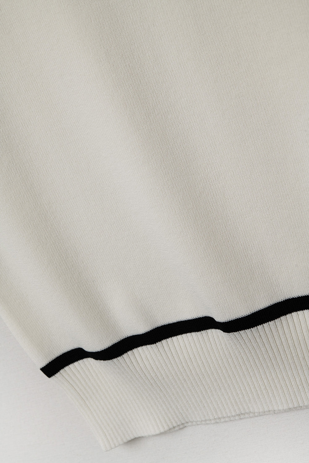 Mouwloze trui in wit met zwarte lijnen aan de buitenkant