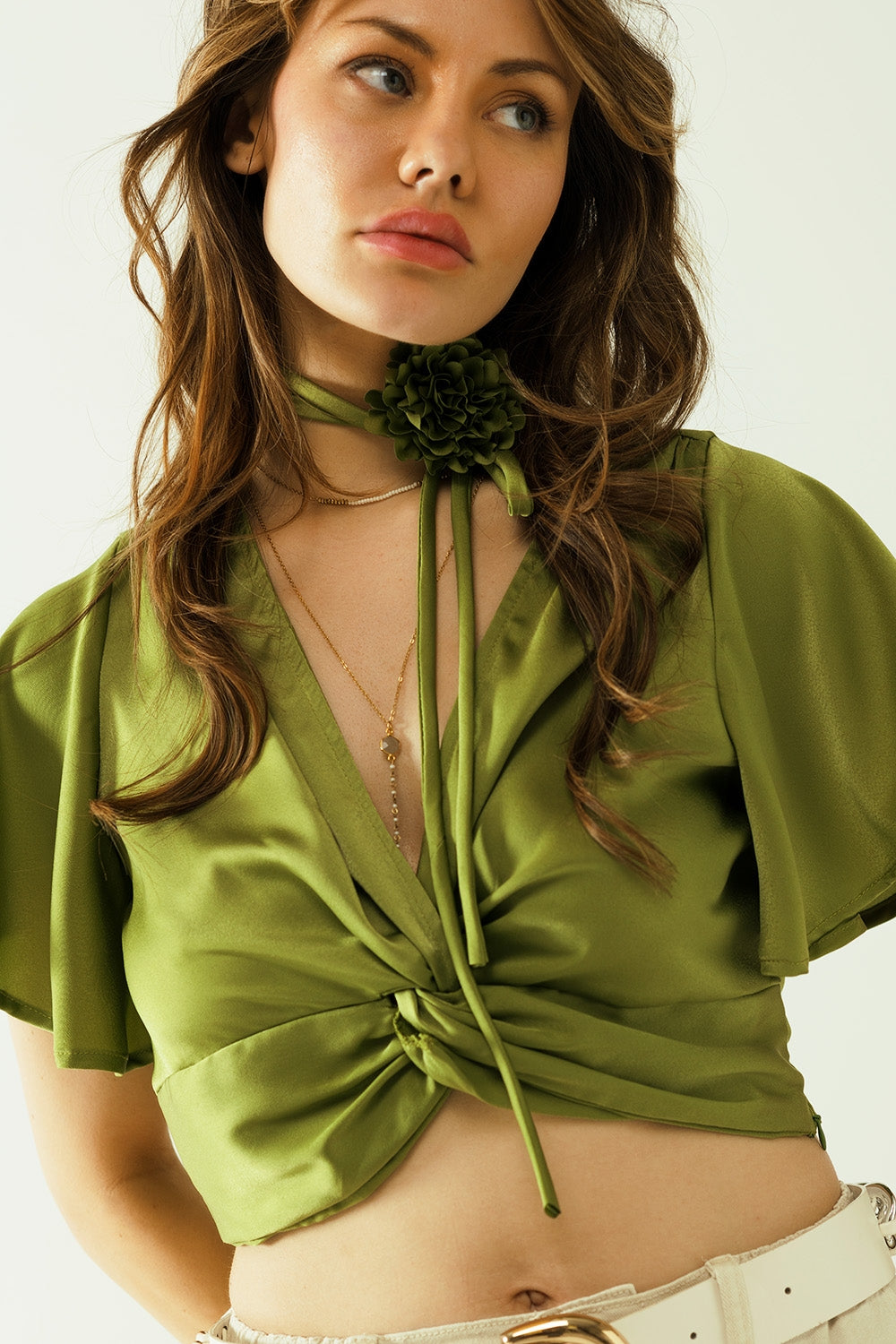 Top curto verde com decote em V, manga curta e detalhe de flor no pescoço