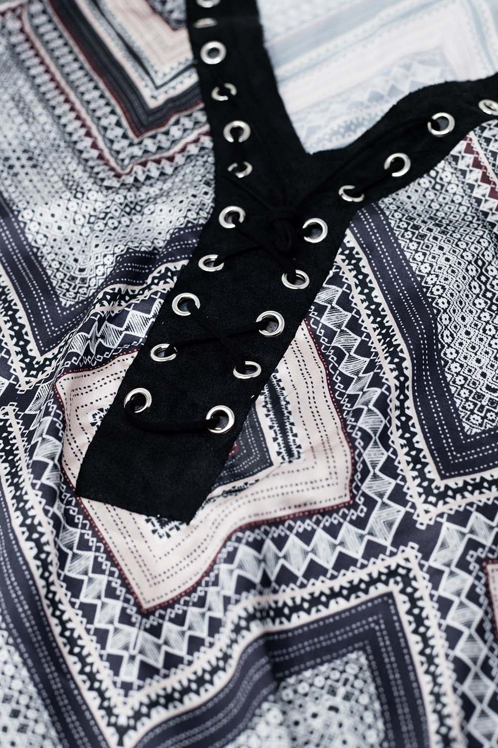 Camisola cinzenta com estampado geométrico e detalhe de amarração cruzada na gola